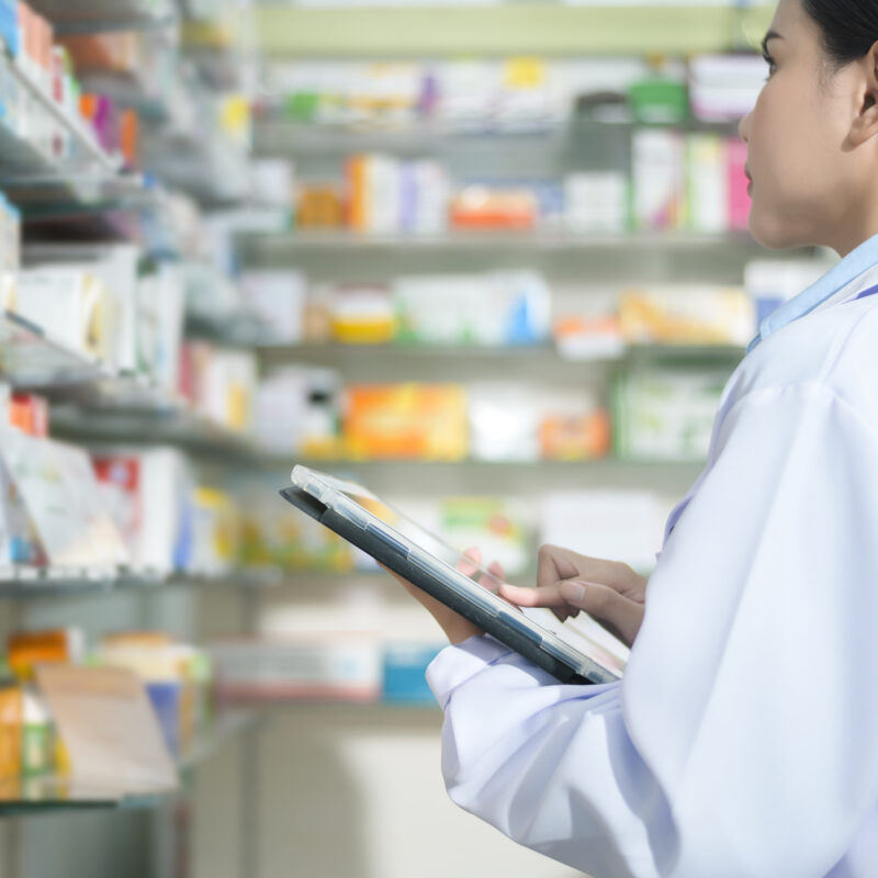 A Portrait of female pharmacist using tablet in a modern pharmacy drugstore.